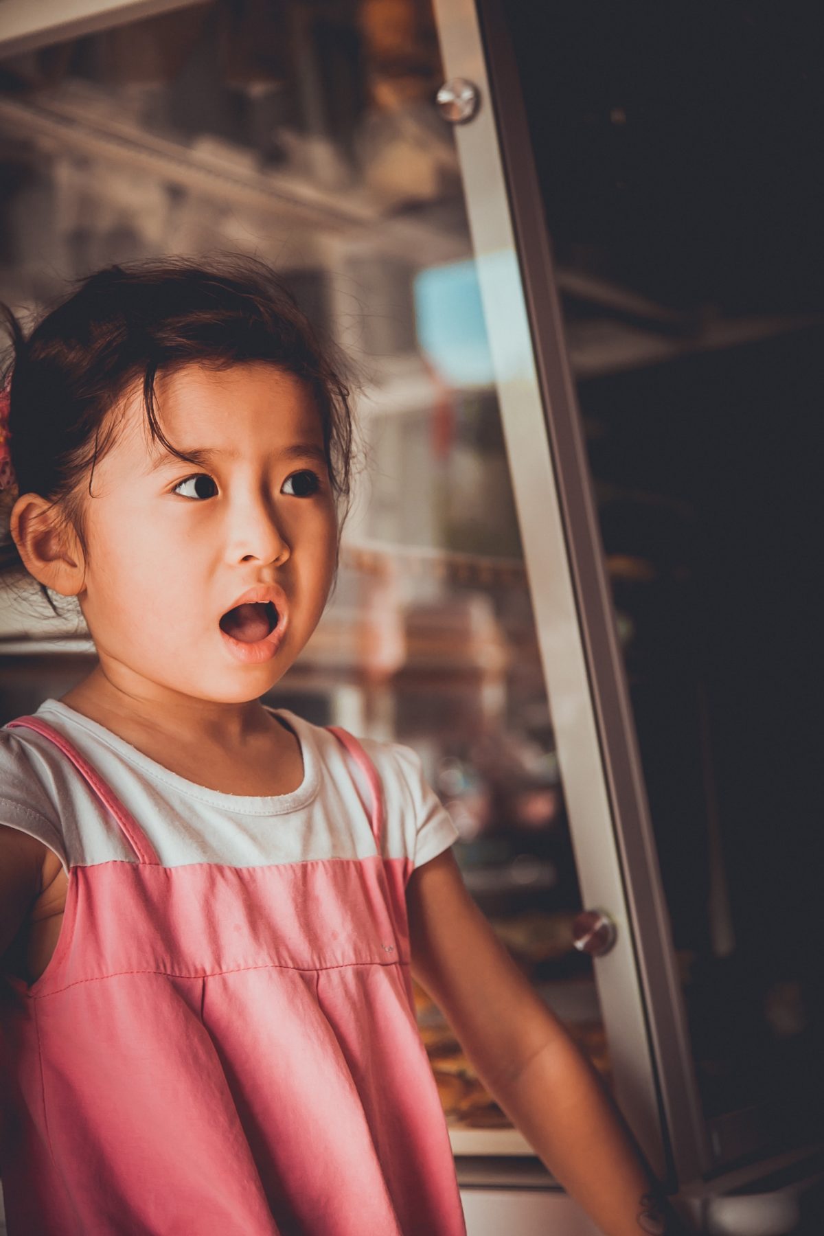 girl standing beside glass window, looking surprised